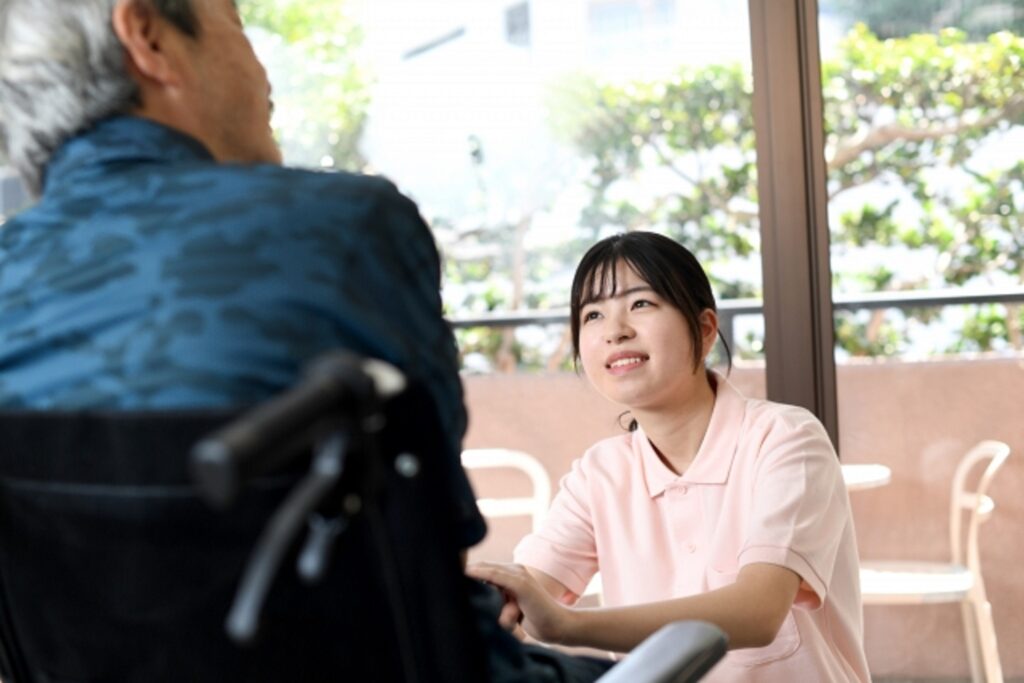 車いすに乗った男性に看護師が話しかけている